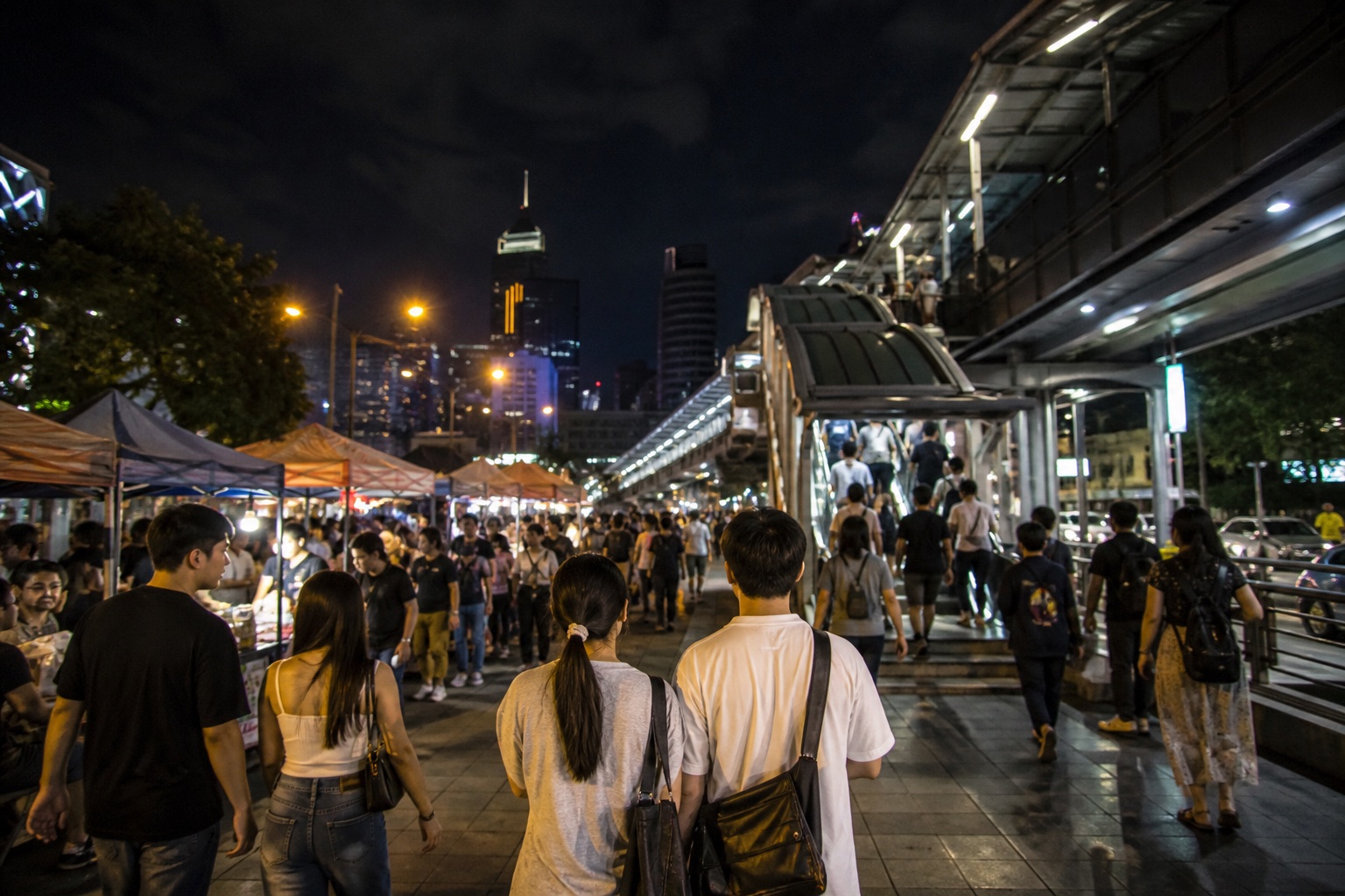 Visitors leaving a Bangkok night market toward public transit