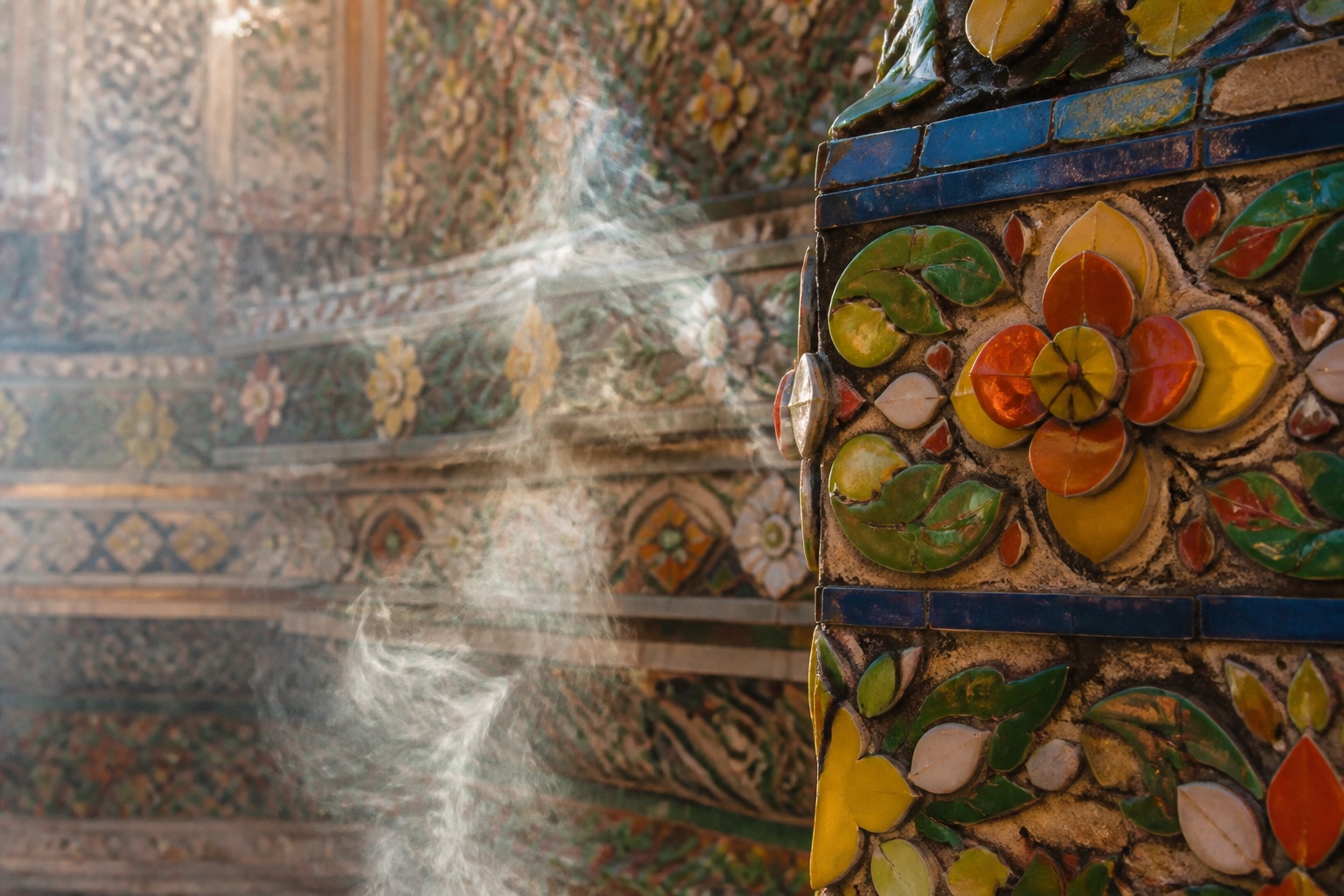 Colorful ceramic mosaic and incense smoke at a Thai temple